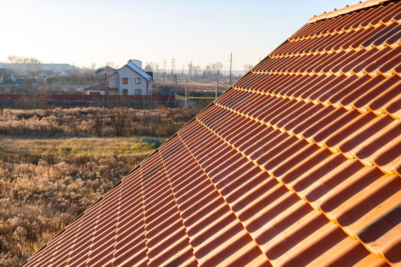 Overlapping rows of yellow ceramic roofing tiles covering residential building roof.